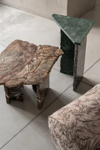 A modern interior design featuring marble side tables on a concrete floor.