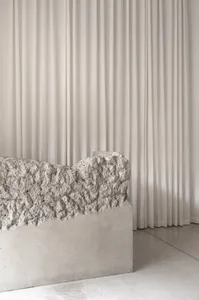 A minimalist bedroom featuring concrete surfaces and a large curtain.