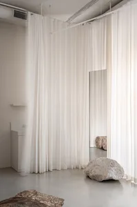 A minimalist interior with textured curtains, rocks, and stone flooring.