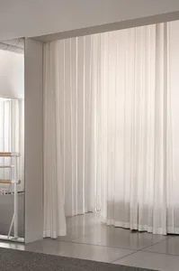 A minimalist interior with floor-to-ceiling white curtains.