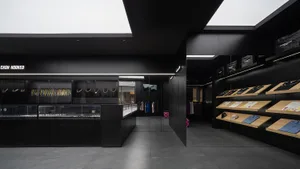 Modern minimalist retail store with black interior, glass display cases, and metallic jewelry display.