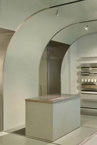 A modern storefront with a concrete exterior, illuminated by track lighting.