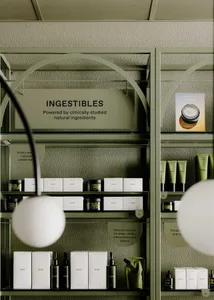 Modern retail interior showcasing cosmetic products on metal shelves with green glass containers.