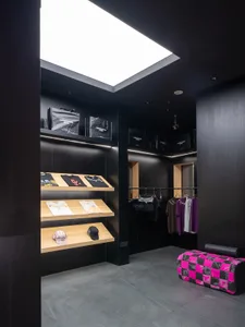 Modern retail store with dark interior, featuring clothing and accessories displayed on shelves.