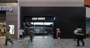 一間現代零售店面，特色為黑色強調牆面，牆上寫著「CASH HOOKED」，攝於街角位置。