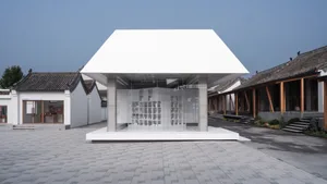 Modern exhibition space with glass walls and a white canopy.