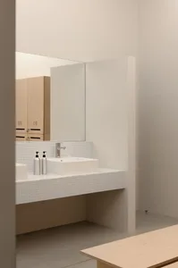 Modern bathroom with white tile, wooden vanity, and metal sink fixture.