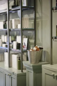 Retail cosmetics store display featuring metal containers with bottles of orange liquid and glass shelving.