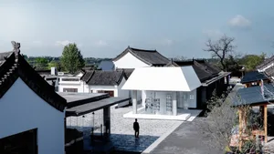 A white pavilion with a white roof in a landscaped outdoor setting.