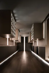 A minimalist corridor featuring wooden panels, metal accents, and illuminated lighting.
