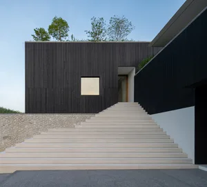 Modern staircase leading up to a building with black walls.