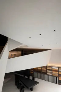 A sleek, minimalist interior space with concrete walls and a large black dining table.