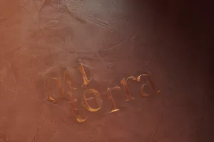 Gold-colored metallic inscription carved into a textured wall, featuring stylized letters spelling 'au terra'.