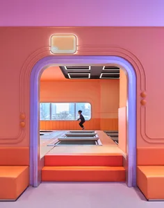 Colorful modern playroom with trampolines and seating areas.