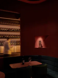 A cozy dining setup featuring a table with a bottle of wine and glasses, surrounded by upholstered seating and a terrazzo cou