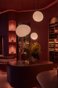 A modern restaurant interior with a terrazzo countertop, pendant lights, and shelves.
