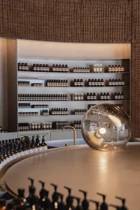 Modern retail storefront with glass shelves displaying bottles of Aesop products.