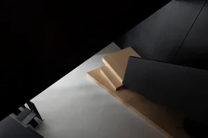 A minimalistic design of wooden stairs with a black wall and floor.