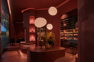 Modern interior design of a wine bar featuring concrete walls, terrazzo flooring, and natural light from large windows.
