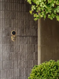Modern building exterior made of concrete tiles with a circular window and cursive text.