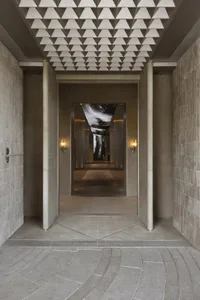 Modern entrance hall featuring a concrete floor and ceiling with geometric patterns.