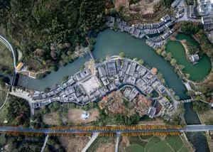 Aerial view of a traditional Chinese village with curved rooftops and a central water feature.