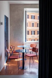 A cafe corner with a metallic black base table and glass top, surrounded by terrazzo flooring, featuring modern furniture and