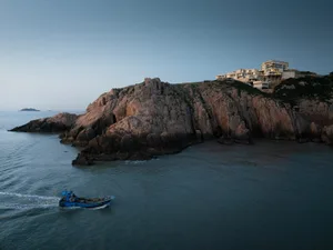 A boat航行在海岸边的悬崖和岩石海岸线上