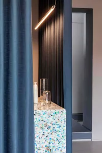A modern bar with a colorful speckled concrete countertop and blue curtains.