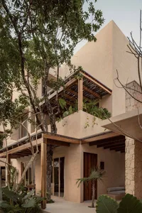 A modern building with a concrete facade and lush greenery surrounding it.