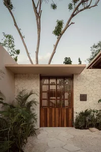 Modern entranceway featuring a wooden double door with a疼痛守卫, surrounded by natural greenery and textured stone pathway.