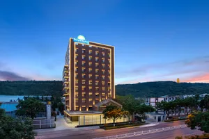 Modern hotel building exterior with concrete, glass, and illuminated lighting features.
