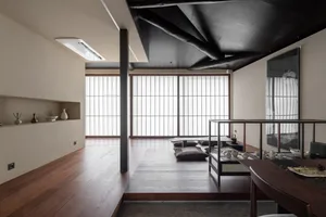 A modern indoor space featuring wooden flooring, minimalist furniture, and natural light through multiple windows.