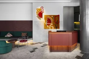 Modern hotel reception area with colorful abstract wall art and mixed materials.