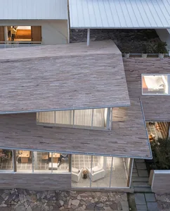 A modern house with wooden exterior and large windows overlooking a courtyard.
