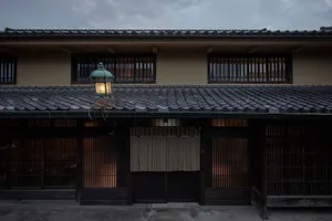 A traditional Japanese building with a grey tiled roof and wooden shutters.