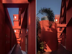 A photograph showcasing the exterior of a red building with a cement drainage system, emphasizing architectural lines and sha