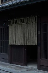 A traditional Japanese storefront with a rope curtain hanging from above.
