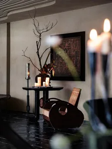 A modern living space with a decorative arrangement featuring candles, a vase with dried branches, and an abstract painting.