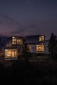 Modern residential house with glass exterior walls illuminated at night.