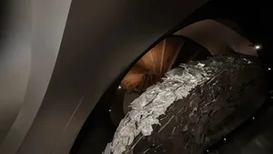 A modern metal sculpture with a rough, textured surface.