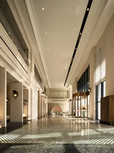 A spacious hotel lobby featuring modern lighting, concrete finishes, and glass details.