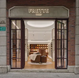 The storefront of the Frette store with large glass doors and brick walls.