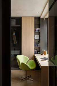 A modern minimalist workspace featuring a green chair and a desk with books and a laptop.