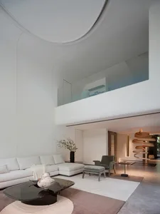 A modern, minimalist living room with white furniture and a sleek, curved design.