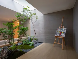 A modern indoor garden area with concrete walls, wooden floors, and decorative rocks.
