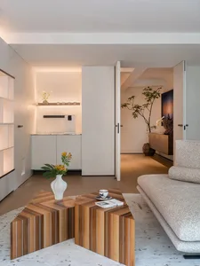 A modern living room with a wooden table, fabric sofa, and marble accents.