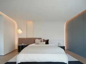 A modern minimalist bedroom with a king-sized bed, beige headboard, and white bedding. The room features a large window allow