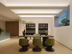 A modern tea room featuring wooden flooring, glass shelving units filled with ceramic tea pots and cups, green plants, and bl