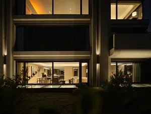 Modern house exterior with illuminated windows and glass doors.